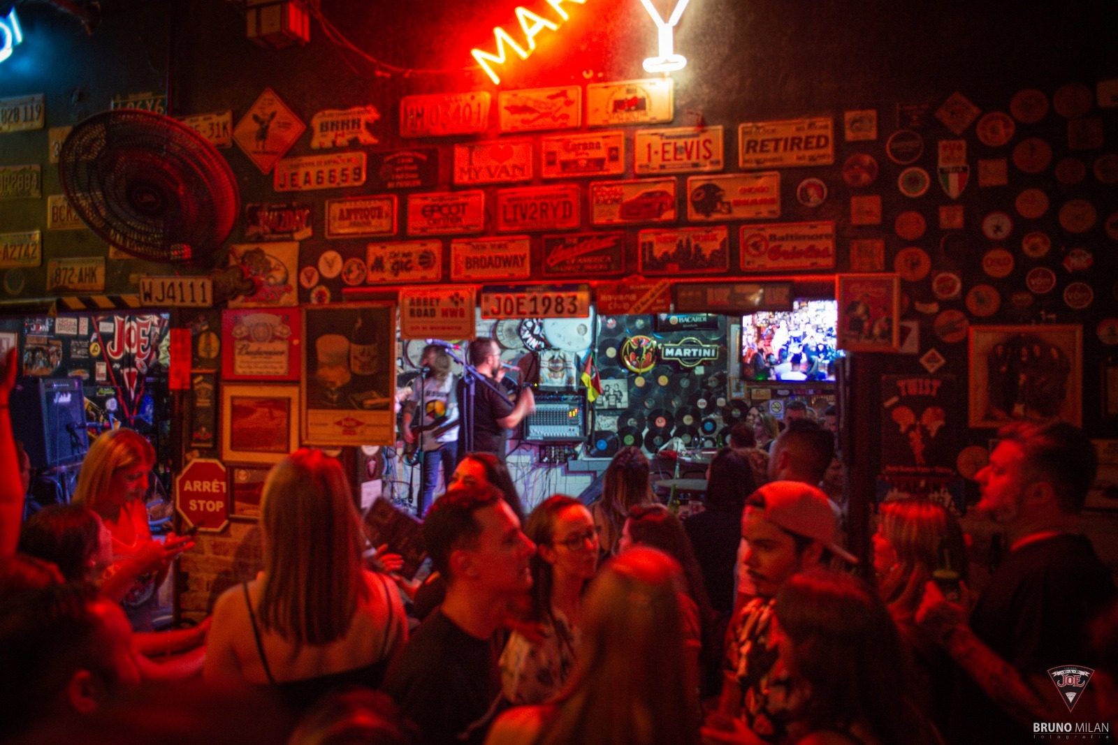 Bar com iluminação vermelha e diversas placas e adesivos vintage nas paredes