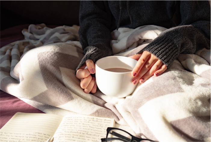 Moça na cama tomando café e lendo