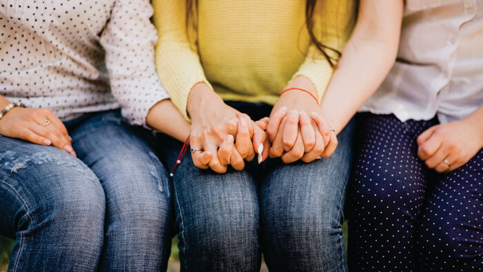 Mulheres sentadas de mãos dadas