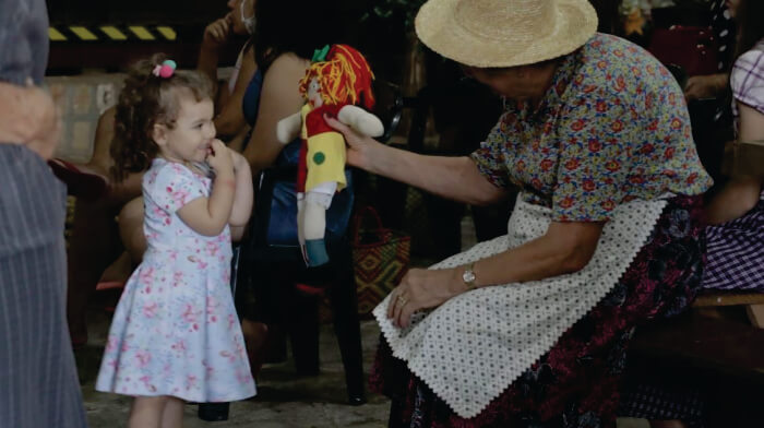 Mulher dando boneca da Emília para criança