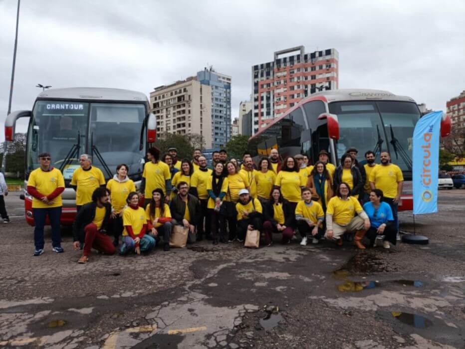 Pessoas de amarelo em frente a ônibus