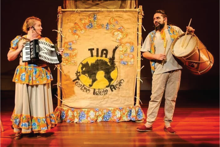 Homem e mulher tocando instrumentos musicais em palco